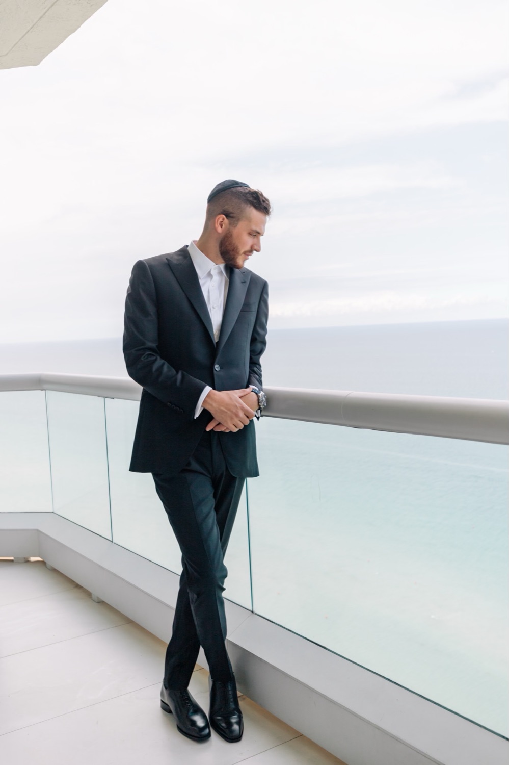 Man in a black Oliel suit on an oceanfront balcony, Miami