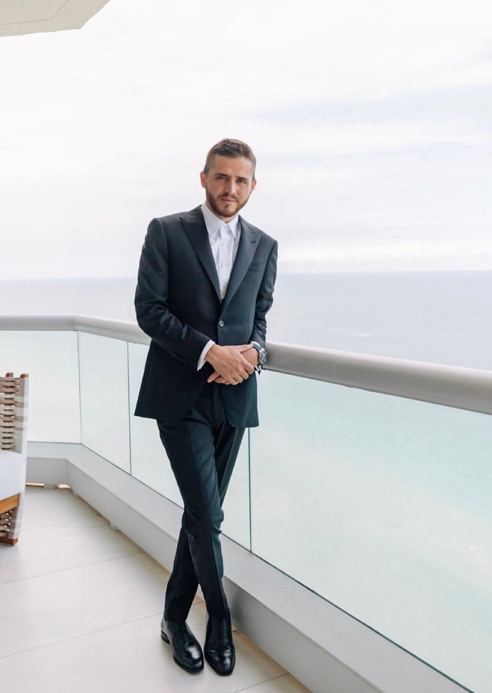Client in a bespoke Oliel suit on an oceanfront balcony