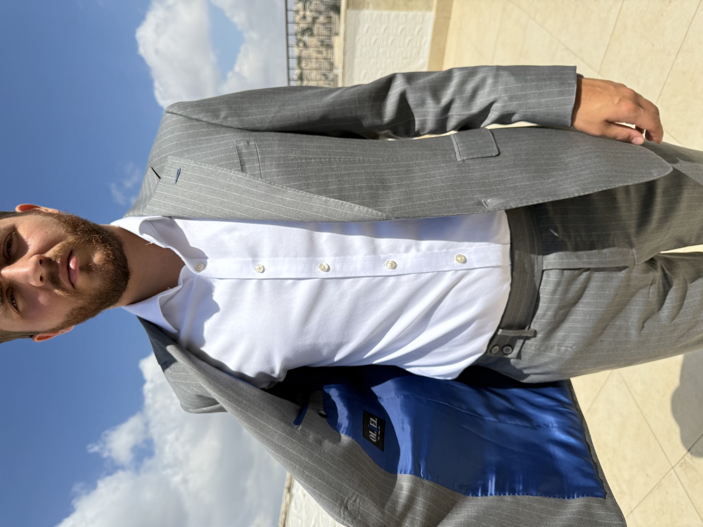 Client in a grey pinstripe Oliel suit on a rooftop